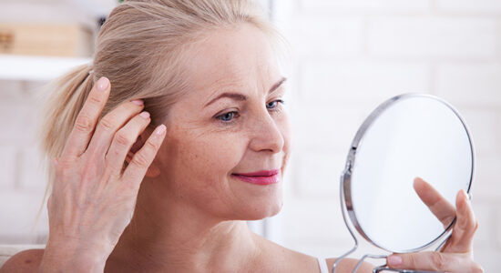 Middle aged woman looking at wrinkles in mirror. Plastic surgery and collagen injections. Makeup. Macro face. Selective focus on the face. Realistic images with their own imperfections.